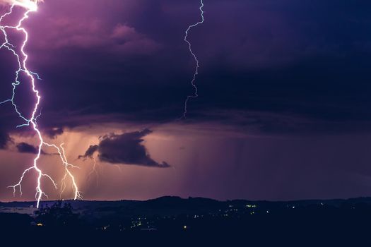 Night landscape on a background of thunderstorms. Rural silhouette and clouds with lightning flashes