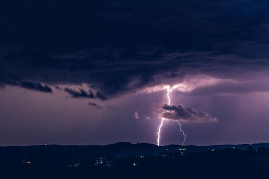 Night landscape on a background of thunderstorms. Rural silhouette and clouds with lightning flashes