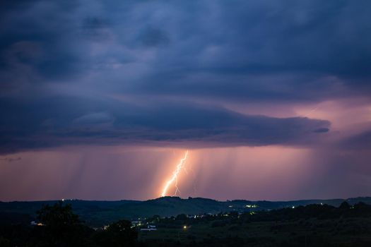 Night landscape on a background of thunderstorms. Rural silhouette and clouds with lightning flashes