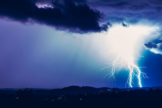 Night landscape on a background of thunderstorms. Rural silhouette and clouds with lightning flashes