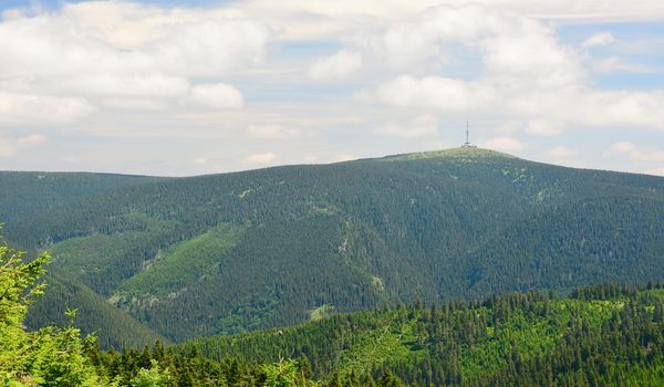 View of Praded mountain with TV (television) tower (transmitter) in Jeseniky mountains, Czech Republic. Cloudy sky.