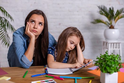 Mother becoming frustrated with daughter whilst doing homework sitting at the table at home in learning difficulties homework. Parenting and education concept