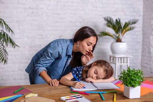 Mother becoming frustrated with daughter whilst doing homework sitting at the table at home in learning difficulties homework. Parenting and education concept