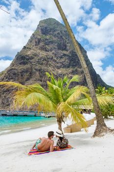 couple sunbathing on the beach during summer vacation on a sunny day, men and woman on vacation at the tropical Island of Saint Lucia Caribbean. Sugar beach St Lucia Caribbean