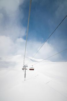 ski lift high in the clouds against the backdrop of snow-capped mountains, vertical orientation.