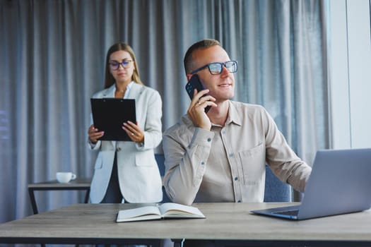 A business woman and a business man are discussing work in the office. Modern office. Colleagues in the office.