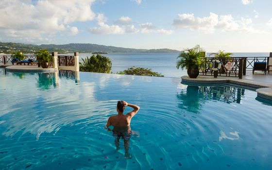 Young men in a swim shorts at Saint Lucia Caribbean, men at infinity pool during sunset. man in a swim short at the pool