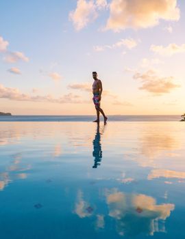 Young men in a swim shorts at Saint Lucia Caribbean, men at infinity pool during sunset. man in a swim short at the pool