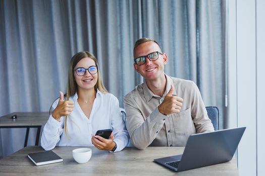 Young business team, male and female colleagues talking at work, discussing a new project with a laptop, young executives having a friendly conversation, collaborating in teamwork in the office