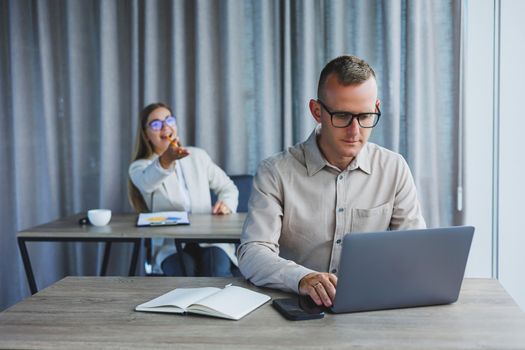 Portrait of a cheerful man, IT professional, working with a modern laptop, sitting at a table and smiling at the camera during a break, a happy human programmer in vision correction glasses