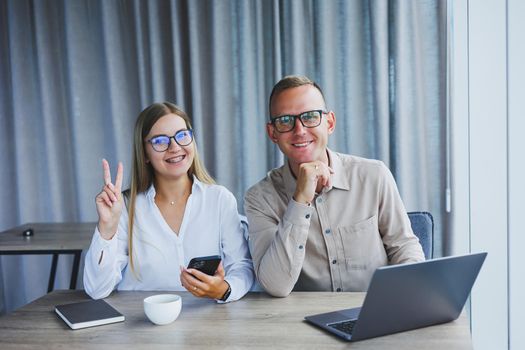Young business team, male and female colleagues talking at work, discussing a new project with a laptop, young executives having a friendly conversation, collaborating in teamwork in the office