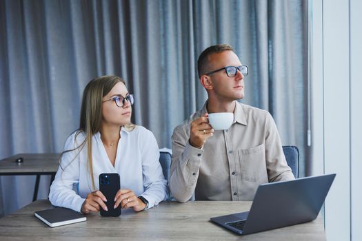 Young business team, male and female colleagues talking at work, discussing a new project with a laptop, young executives having a friendly conversation, collaborating in teamwork in the office