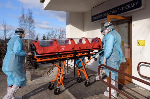 A woman in a hygiene mask and gloves is trying to avoid the coronavirus epidemic. Transportation of the patient in a protective box.