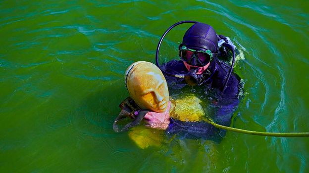 scuba diving training for lifeguards. detection of people. lifeguard is training with a dummy.
