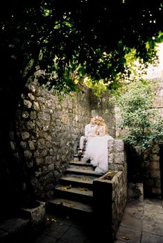 Bride and groom are sitting on the ancient stone steps. High quality photo