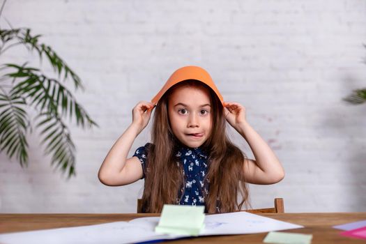 Cute little girl at the table with the colored paper