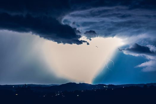 Night landscape on a background of thunderstorms. Rural silhouette and clouds with lightning flashes