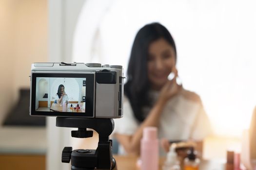 Young beautiful Asian woman and professional beauty make up artist vlogger or blogger recording makeup tutorial to share on website or social media. Business online influencer on social media concept.