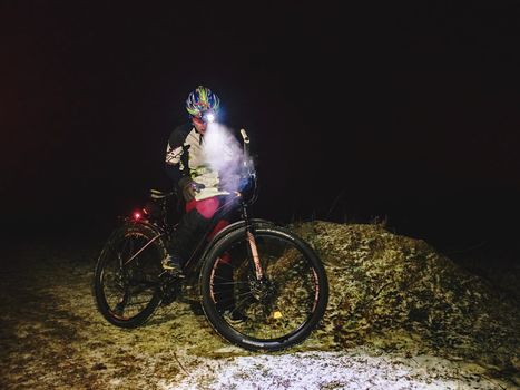 Outdoor orienteering extreme bike race in night. January 25th 2019, Novy Bor, Czech Republic. Woman check the map. Kind of sports that require navigational skills using a map and compass to achieve target.