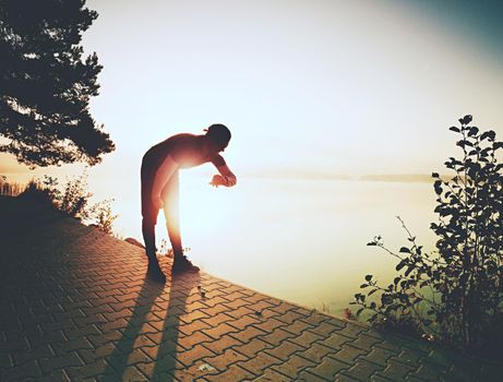 Runner tired exhausted during cardio effort using his wearable technology smartwatch checking heart rate monitor. Outdoor run at lake