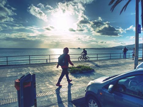 Pedestrians and biker on pavement at sea shore, promenade  at Palma de Mallorca city, 26th of January 2020