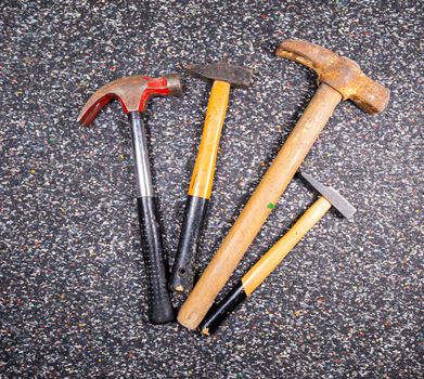assortment of different old and used hammers on a dark colorful background.