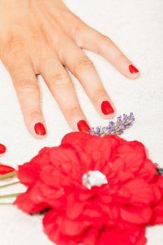 Hands of a woman with red nail polish posed by an esthetician