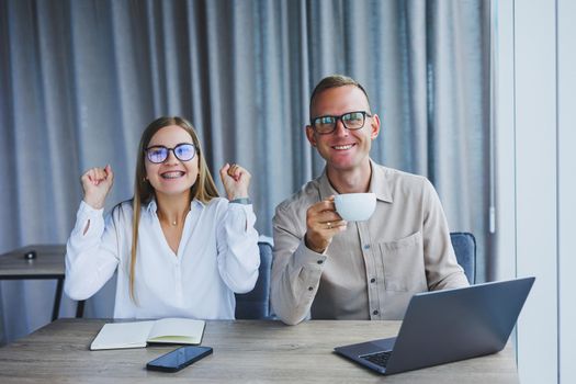 Young business team, male and female colleagues talking at work, discussing a new project with a laptop, young executives having a friendly conversation, collaborating in teamwork in the office