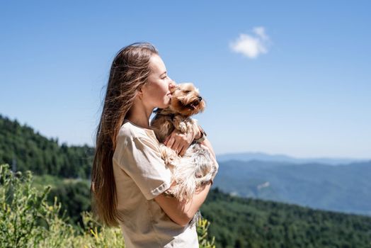 Pet care. Travelling. Young pretty caucasian woman smiling holding small dog yorkshire terrier. Woman travel with pet, looking at view