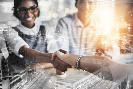 Striking a deal. two young businesspeople shaking hands during a meeting in the boardroom