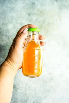 Woman hand holds homemade juice in the bottle