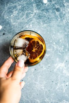 Alcohol cocktail with coke in the glass with orange and ice in woman hand