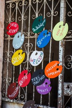 Wooden board with Welcome words in many languages on the old entrance gate