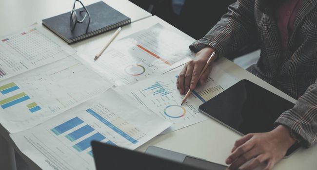 Close up of accountant working and analyzing financial reports project accounting with chart graph and calculator in modern office : finance and business concept..