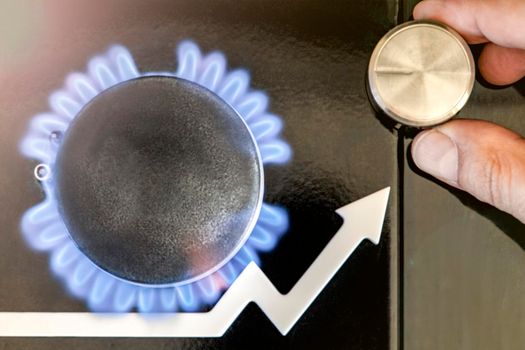 Gas price. Supply chains and the energy gas crisis. Gas stove with a burning flame and a graph arrow pointing up. Man's hand adjusts the gas supply.