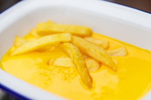 The concept of fast food and fast food. French fries sit in a plate along with cheddar cheese sauce. Top view, close-up