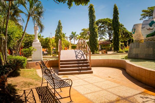 A nice and relaxed park with a wooden bridge over a water fountain, Traditional park of Nagarote, Nicaragua. View of a calm park with a small wooden bridge on a sunny day. Nagarote central park