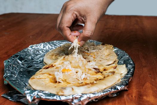 Nicaraguan pupusas with salad on aluminum foil, View of delicious Salvadoran pupusas served on wooden table. Traditional pupusas served with salad on the table