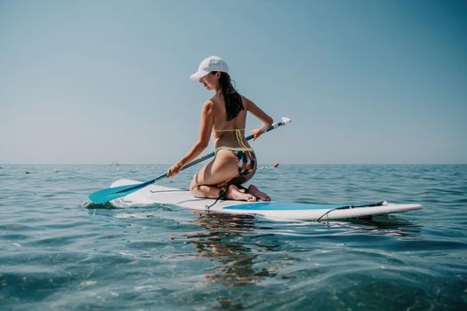 young woman in swimsuits doing yoga on sup board in calm sea, early morning. Balanced pose - concept of healthy life and natural balance between body and mental development