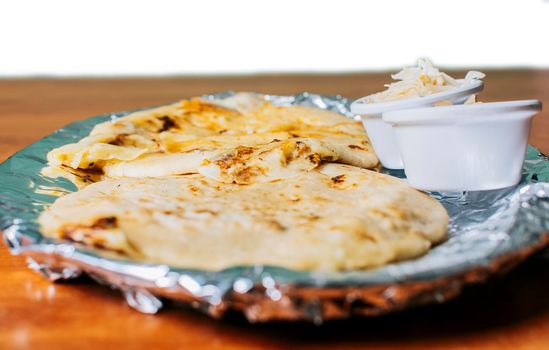 Traditional pupusas served with salad on the table. Two Nicaraguan pupusas with salad on the table, Side view of delicious Salvadoran pupusas with cheese served on the table.