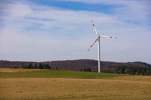 Aerial view of a wind turbine with red and white rotor blades in a rural landscape