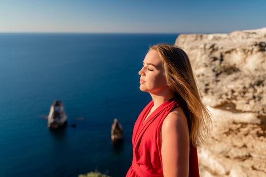 A woman in a red flying dress fluttering in the wind, against the backdrop of the sea