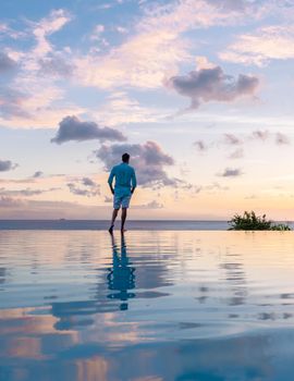 Young men watching the sunset with reflection in the pool at Saint Lucia Caribbean, men at infinity pool during sunset