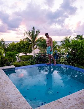 Young men watching the sunset with reflection in the pool at Saint Lucia Caribbean, men at infinity pool during sunset