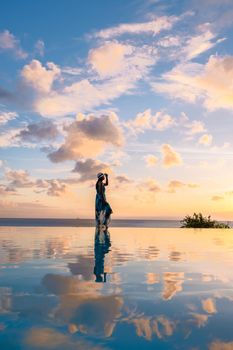 Young women watching the sunset with reflection in the infinity swimming pool at Saint Lucia Caribbean, Asian women at infinity pool during sunset