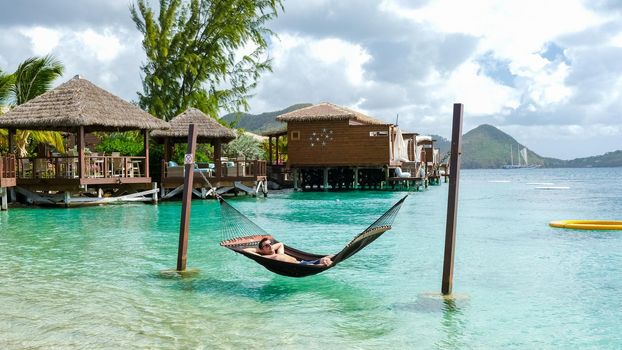 young men in hammocks in the ocean at the beach of the tropical Island in the Caribbean. luxury holiday vacation on a tropical island