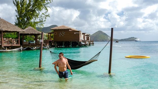 young men in hammocks in the ocean at the beach of the tropical Island in the Caribbean. luxury holiday vacation on a tropical island