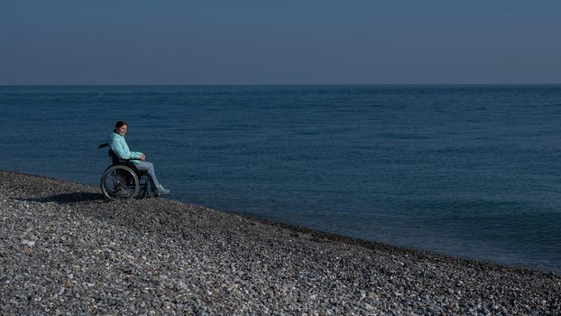 Pacified caucasian woman in a wheelchair on the seashore