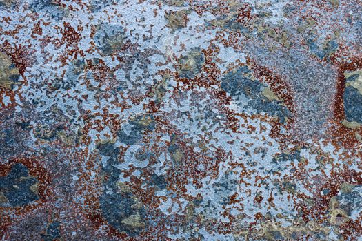 Abstract background of peeling old brown paint with blue spots showing through.