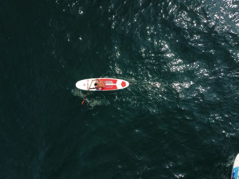 young man swimming in sea water and paddleboarding passing beautiful sea at summer sunset. Healthy strong male enjoy outdoor active lifestyle and water sports on holiday vacation